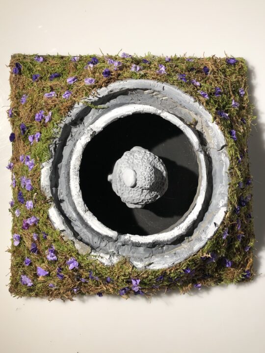 Photograph of a model of a concrete form surrounded by moss