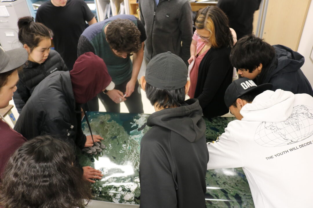 Photograph of community members speaking over a site map