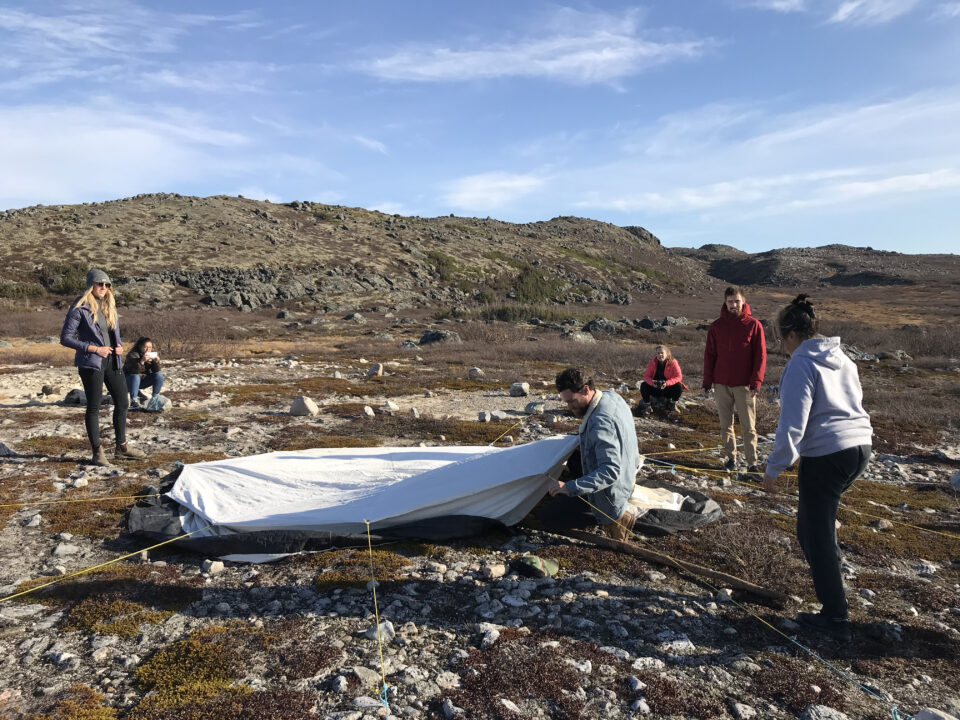 Photograph of students setting up a tarp on a barren landscape