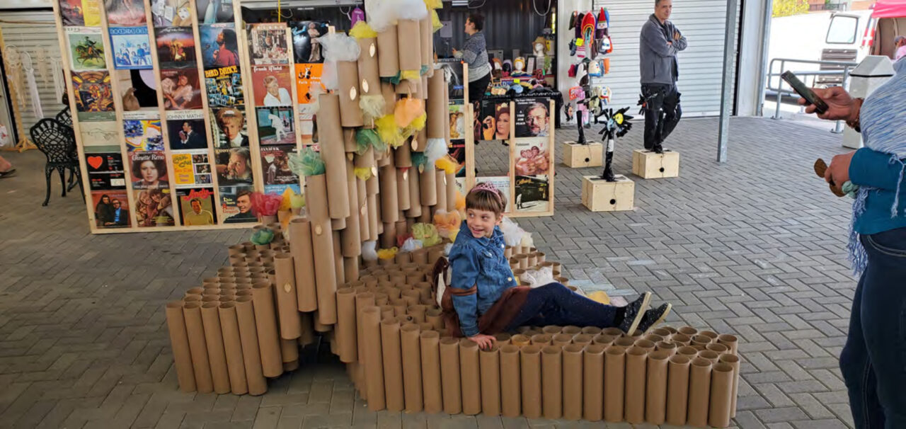 Photograph of a child sitting on a student made structure of cardboard tubes