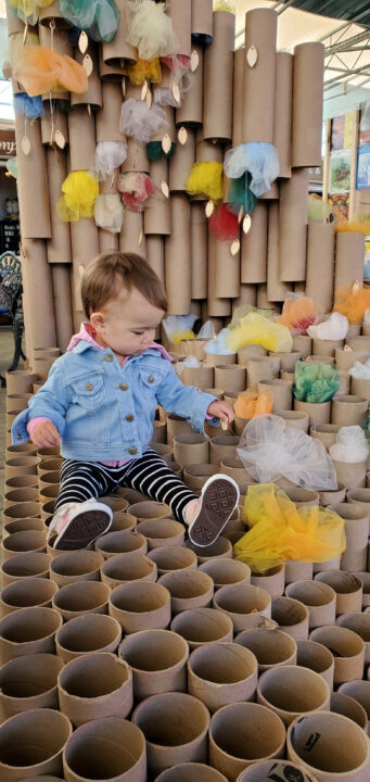 Photograph of a child sitting on a student made structure of cardboard tubes