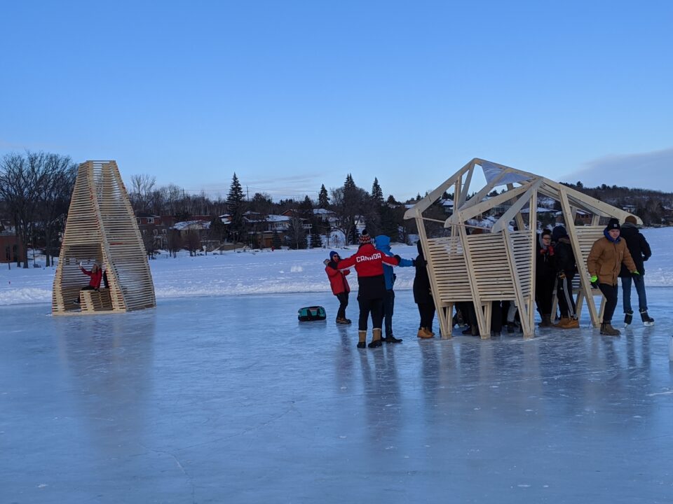Photograph of two of the student made wooden ice stations with people skating and interacting with them