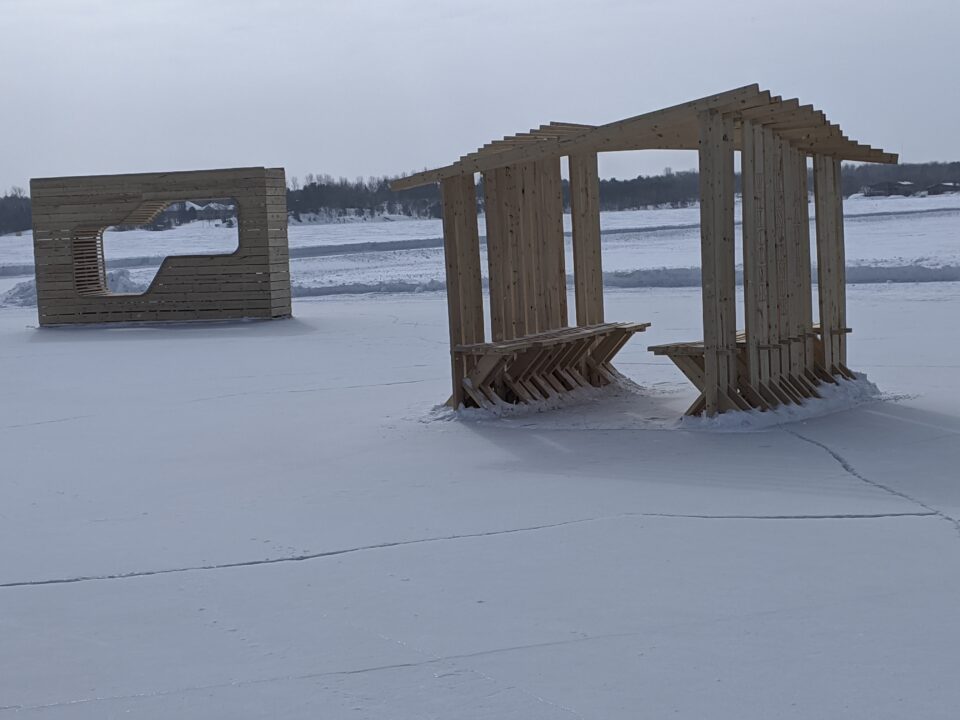Photograph of two student made wooden ice huts on a skating path in winter