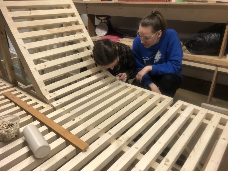 Photograph of two students working on the construction of their wooden ice hut