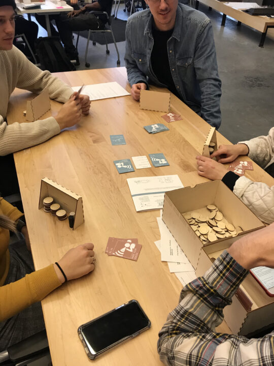 Photograph of students playing the board games they designed at multiple tables