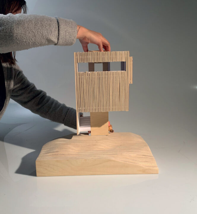 Photograph of a student holding up a tall wooden model