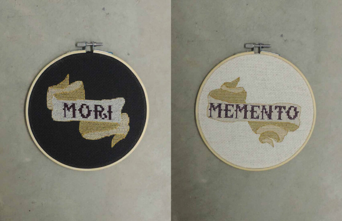 Photograph of two embroidery circles, one with the latin word, mori, on a black background and the other with the latin word, memento, on a white background