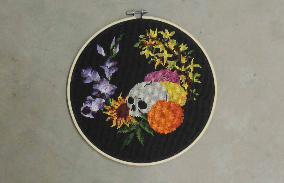 Photograph of a skull and flower embroidery piece with a black background