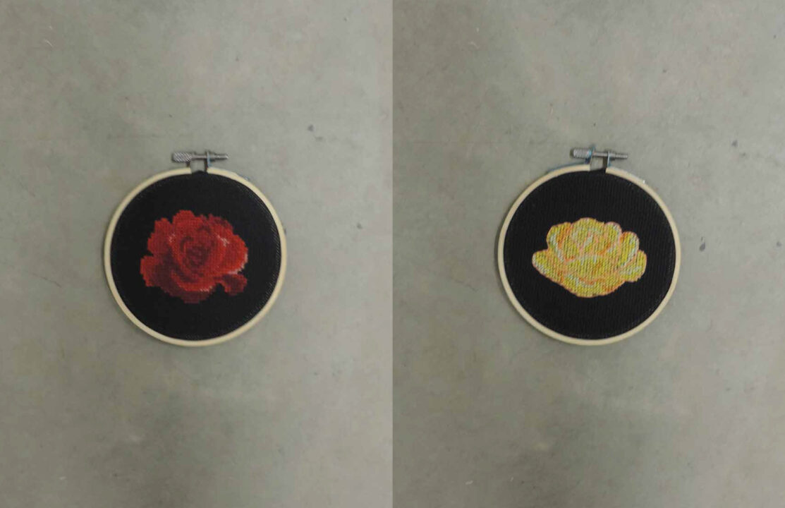 Photograph of two embroidery circles, one with a red rose on a black background and the other with a yellow rose on a black background