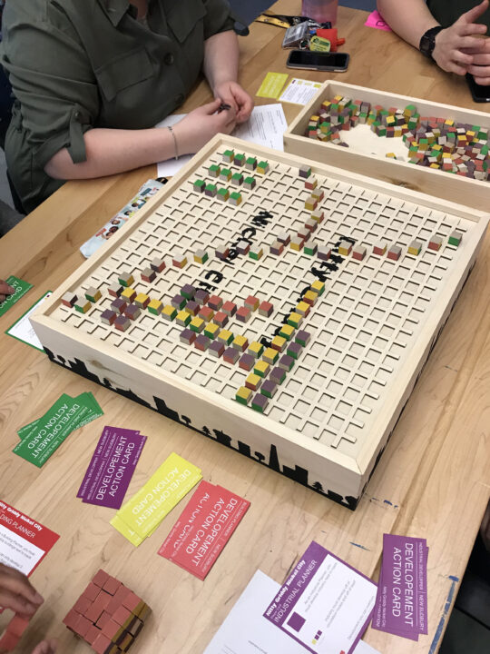Photograph of a student designed board game with small square slots to fit wooden blocks into